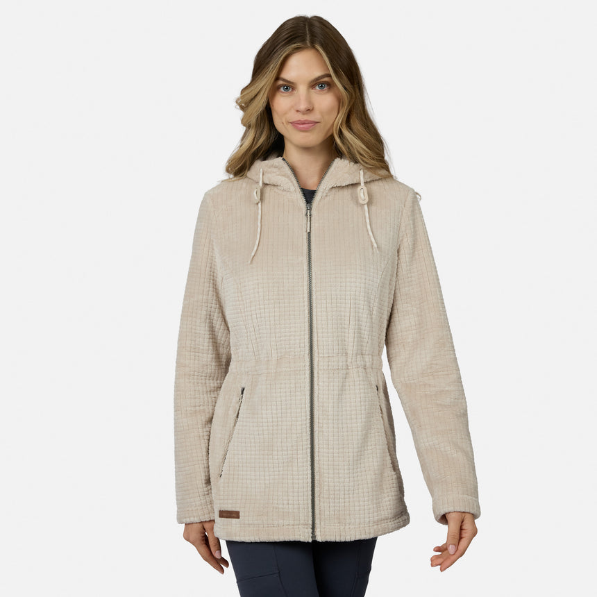 A woman with long, wavy hair wears the Free Country Women’s Grid Butter Pile® Anorak Jacket in light beige, featuring drawstrings, standing against a plain white background.