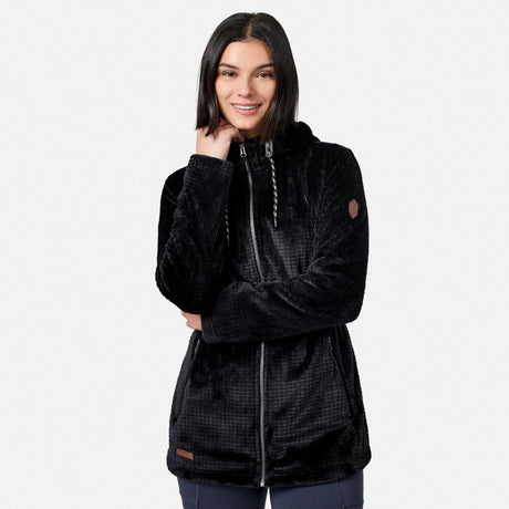 A woman with straight dark hair is smiling and posing with one hand near her neck, wearing the Free Country Women’s Grid Butter Pile® Anorak Jacket in black, against a plain light background.