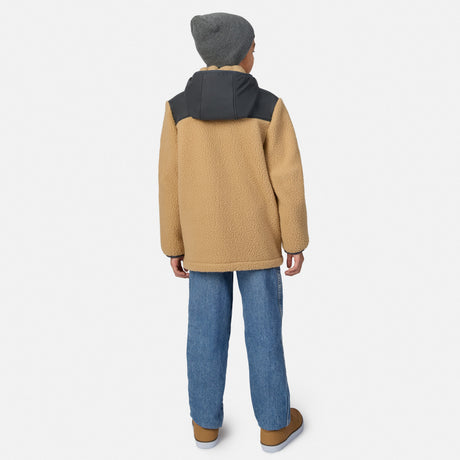A child shown from the back wearing a tan fleece jacket with a dark gray hood, blue jeans, and brown shoes against a light gray studio background.