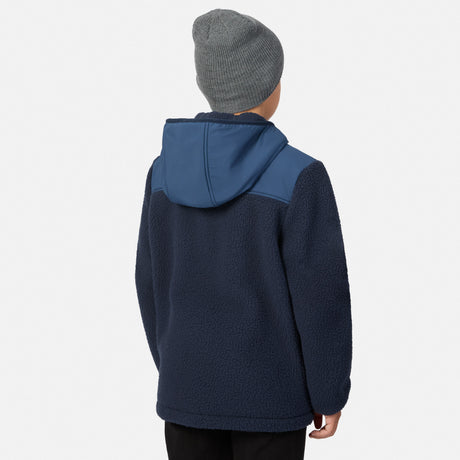 A child shown from the back wearing a navy fleece hooded jacket with a contrasting blue hood panel and a gray knit beanie, against a light gray studio background.