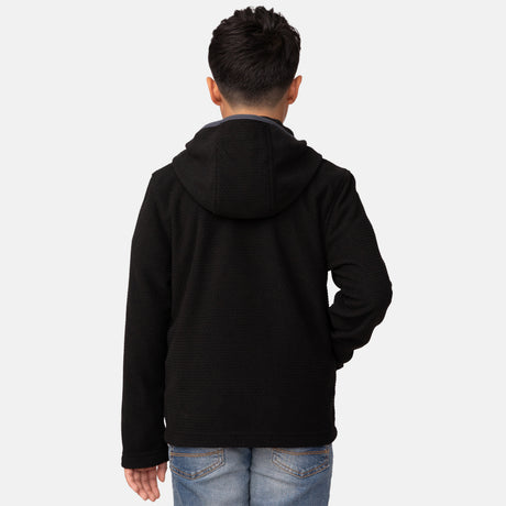 [Model is wearing a size Medium.]  Boy wearing Free Country Boys' Brick Fleece Hoodie Jacket in Black with a soft lining, zipper pocket, smiling with hand in pocket, light grey background