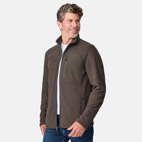 [Kolby is 6'2" wearing size M.] Men’s Free Country brown textured full-zip jacket with high collar and zippered chest pocket in contrast fabric—featuring a streamlined silhouette for cool-weather utility. Paired with blue jeans for a classic, casual outdoor look.