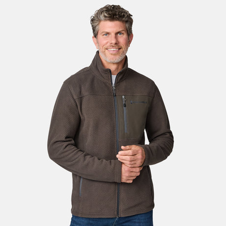 [Kolby is 6'2" wearing size M.] Men’s Free Country brown textured full-zip jacket with high collar and zippered chest pocket in contrast fabric—featuring a streamlined silhouette for cool-weather utility. Paired with blue jeans for a classic, casual outdoor look.