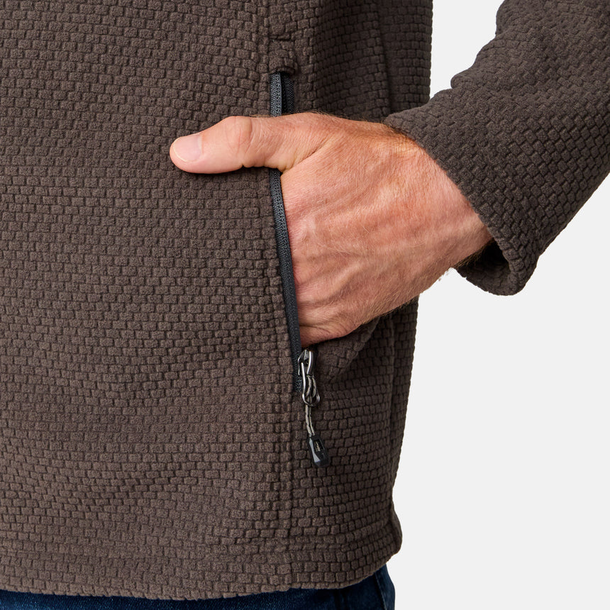 [Kolby is 6'2" wearing size M.] Men’s Free Country brown textured full-zip jacket with high collar and zippered chest pocket in contrast fabric—featuring a streamlined silhouette for cool-weather utility. Paired with blue jeans for a classic, casual outdoor look.