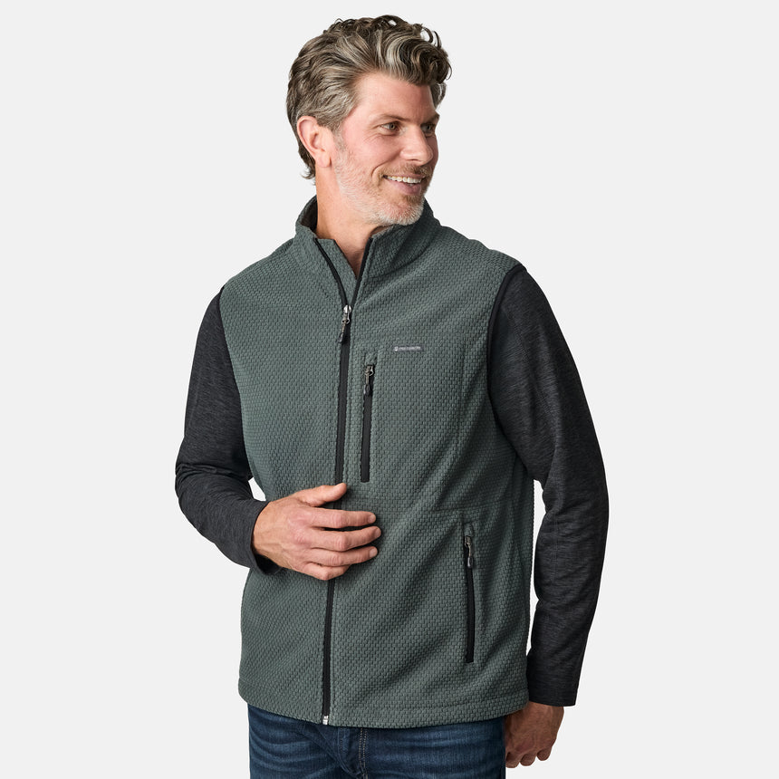 [Kolby is 6'2" wearing size M.] Men’s Free Country green zip-front vest with textured brick pattern and zippered chest pocket—layered over a dark grey long-sleeve shirt and blue jeans. Styled for a laid-back, outdoor-ready look against a clean white background.