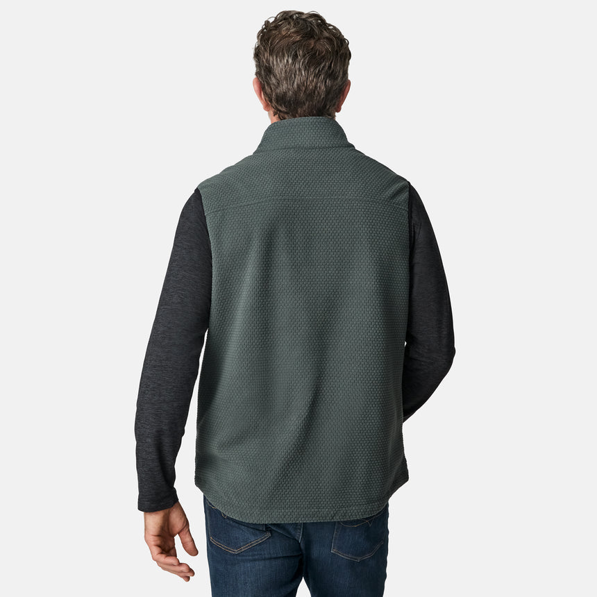 [Kolby is 6'2" wearing size M.] Men’s Free Country green zip-front vest with textured brick pattern and zippered chest pocket—layered over a dark grey long-sleeve shirt and blue jeans. Styled for a laid-back, outdoor-ready look against a clean white background.