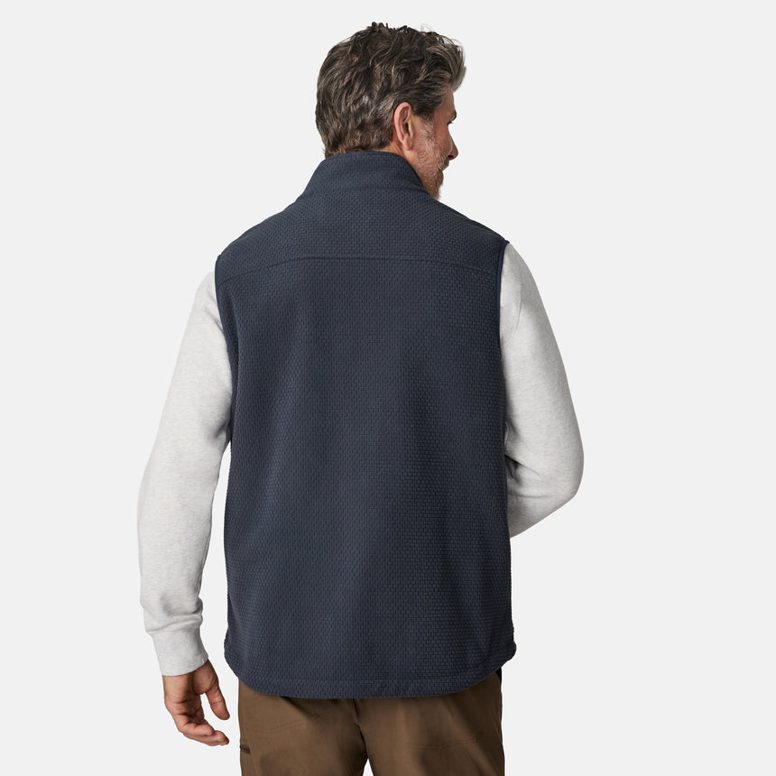 [Kolby is 6'2" wearing size M.] Men’s Free Country navy quilted vest with zippered chest pocket and textured finish—layered over a light gray long-sleeve shirt and brown pants. 