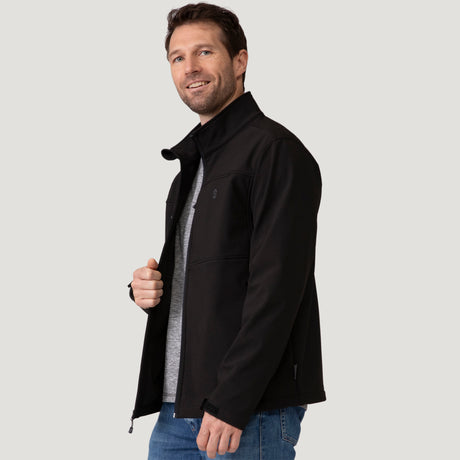 A man wearing a Men’s Stretch Super Softshell® Jacket over a gray t-shirt and blue jeans.