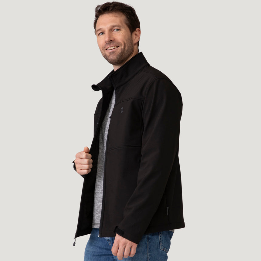 A man wearing a Men’s Stretch Super Softshell® Jacket over a gray t-shirt and blue jeans.