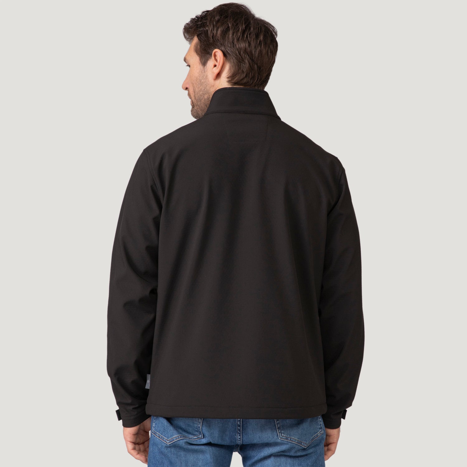 Back view of a man wearing a black Clearance Men’s Stretch Super Softshell® Jacket and blue jeans.