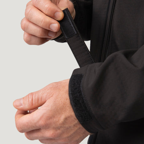 Hands adjusting the hook-and-loop closure on the cuff of a black Men’s Stretch Super Softshell® Jacket.