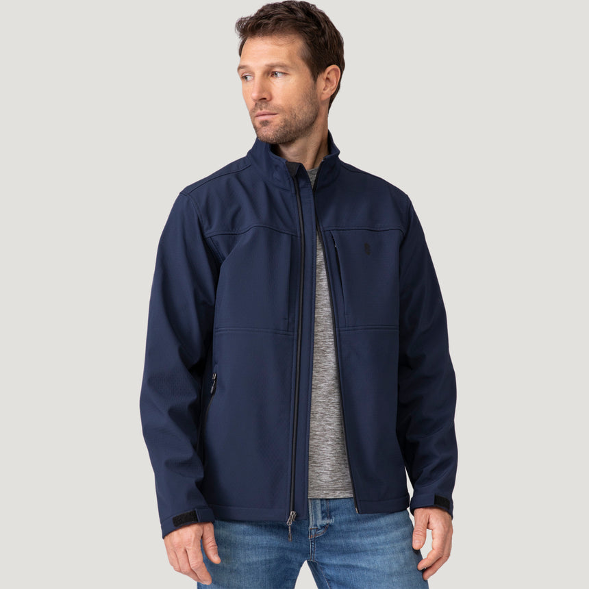A man wearing a navy blue Men’s Stretch Super Softshell® Jacket over a gray t-shirt and blue jeans.