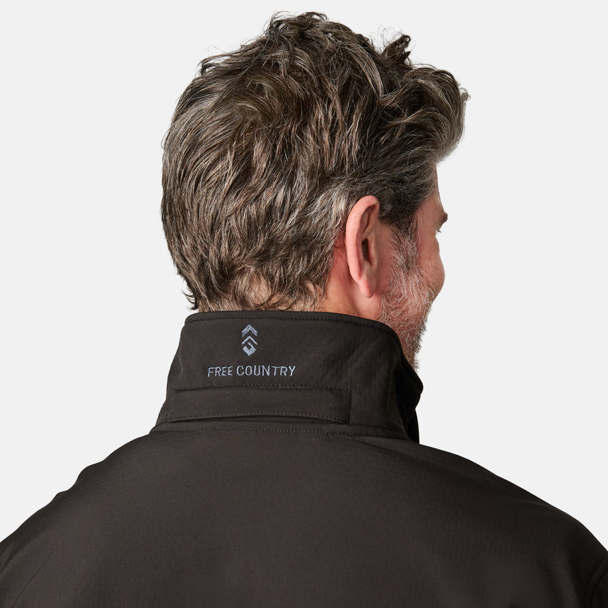 [Kolby is 6'2" wearing size M.] Man wearing Free Country Men's Odyssey II Flex Super Softshell® Jacket in black with a full front zipper opening, adjustable cuff openings, and wind and water resistant stretch performance fabric, light grey background. Perfect men’s jacket for fall weather.