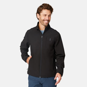 [Matt is 6'2" wearing size M.] Men’s Free Country black zip-front softshell jacket with high stand collar, subtle chest logo, and minimalistic design—featuring streamlined silhouette and long sleeves. Worn with blue pants for a clean, versatile look suited to cool-weather outings.