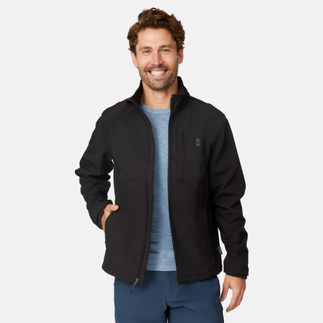 [Matt is 6'2" wearing size M.] Men’s Free Country black zip-front softshell jacket with high stand collar, subtle chest logo, and minimalistic design—featuring streamlined silhouette and long sleeves. Worn with blue pants for a clean, versatile look suited to cool-weather outings.