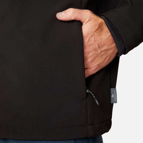 [Matt is 6'2" wearing size M.] Men’s Free Country black zip-front softshell jacket with high stand collar, subtle chest logo, and minimalistic design—featuring streamlined silhouette and long sleeves. Worn with blue pants for a clean, versatile look suited to cool-weather outings.