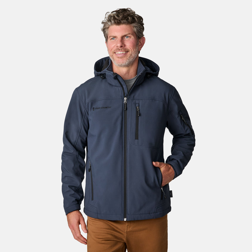 [Kolby is 6'2" wearing size M.] Man wearing Free Country Men's Odyssey II Flex Super Softshell® Jacket in blue with a full front zipper opening, adjustable cuff openings, and wind and water resistant stretch performance fabric, light grey background. Perfect men’s jacket for fall weather.