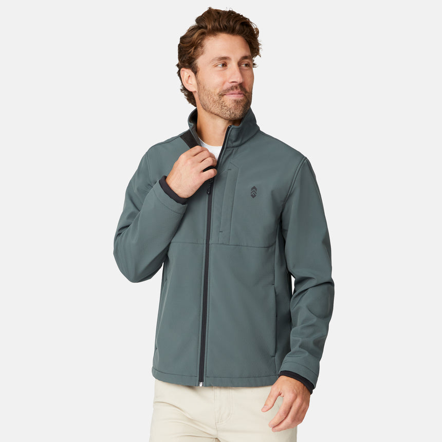 [Matt is 6'2" wearing size M.] Men’s Free Country green zip-front softshell jacket with high stand collar, subtle chest logo, and minimalistic design—featuring streamlined silhouette and long sleeves. Worn with blue pants for a clean, versatile look suited to cool-weather outings.