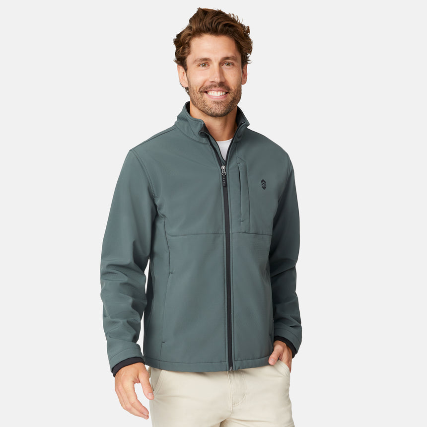 [Matt is 6'2" wearing size M.] Men’s Free Country green zip-front softshell jacket with high stand collar, subtle chest logo, and minimalistic design—featuring streamlined silhouette and long sleeves. Worn with blue pants for a clean, versatile look suited to cool-weather outings.