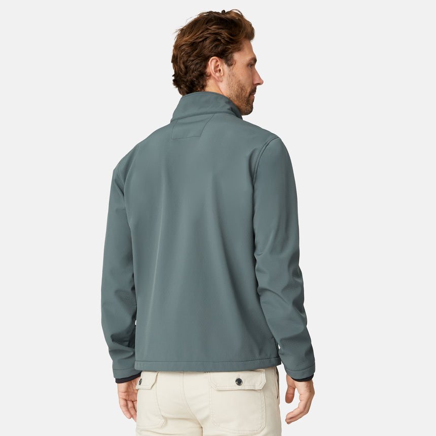 [Matt is 6'2" wearing size M.] Men’s Free Country green zip-front softshell jacket with high stand collar, subtle chest logo, and minimalistic design—featuring streamlined silhouette and long sleeves. Worn with blue pants for a clean, versatile look suited to cool-weather outings.