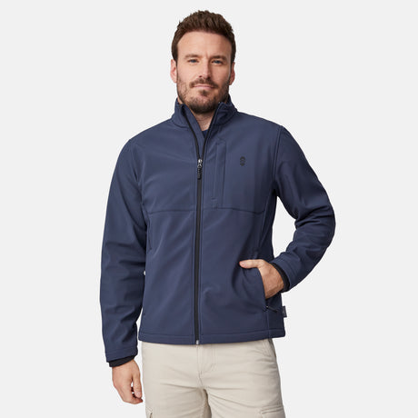 [Joe is 6'0" wearing size M.] Men’s Free Country navy blue zip-front softshell jacket with high stand collar, subtle chest logo, and minimalistic design—featuring streamlined silhouette and long sleeves. Worn with blue pants for a clean, versatile look suited to cool-weather outings.