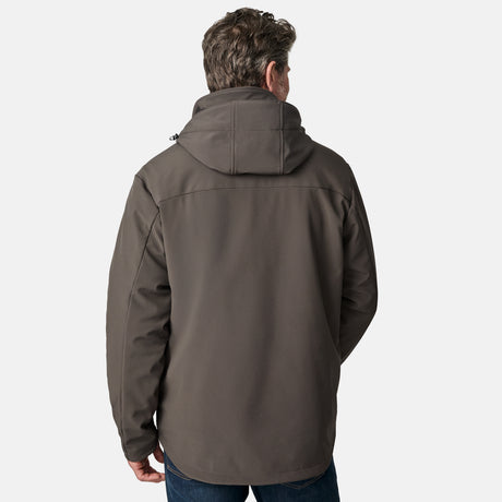A man wearing the Free Country Men's Atalaya III 3-in-1 Systems Jacket in gray and blue jeans stands facing away from the camera against a plain white background.