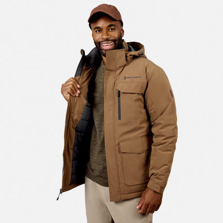 [Model is wearing size M.] A man wearing a brown hooded puffer jacket by North Mountain, styled over a gray sweater and beige pants, standing against a light gray studio background.