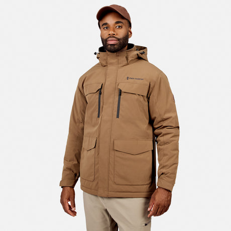 [Model is wearing size M.] A man wearing a tan hooded outdoor jacket with multiple zippered and flap pockets, paired with light khaki pants and a brown cap, photographed against a light gray studio background.