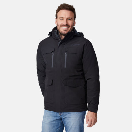 [Joe is 6'0" wearing size M.] Men’s Free Country black hooded utility jacket featuring dual zippered chest pockets, flap waist pockets, and rugged outdoor styling—paired with blue jeans for a functional, adventure-ready look.