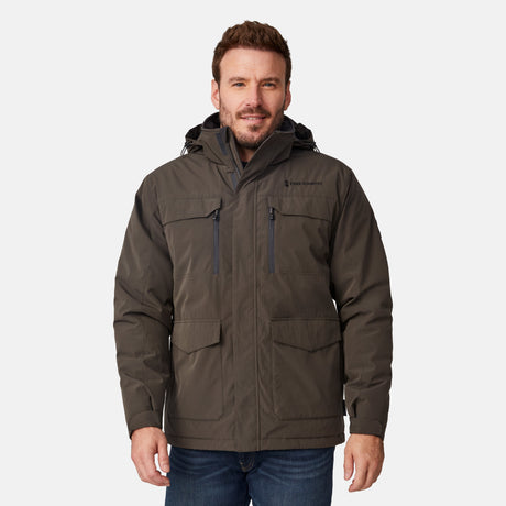 [Joe is 6'0" wearing size M.] Men’s Free Country brown hooded utility jacket featuring dual zippered chest pockets, flap waist pockets, and rugged outdoor styling—paired with blue jeans for a functional, adventure-ready look.