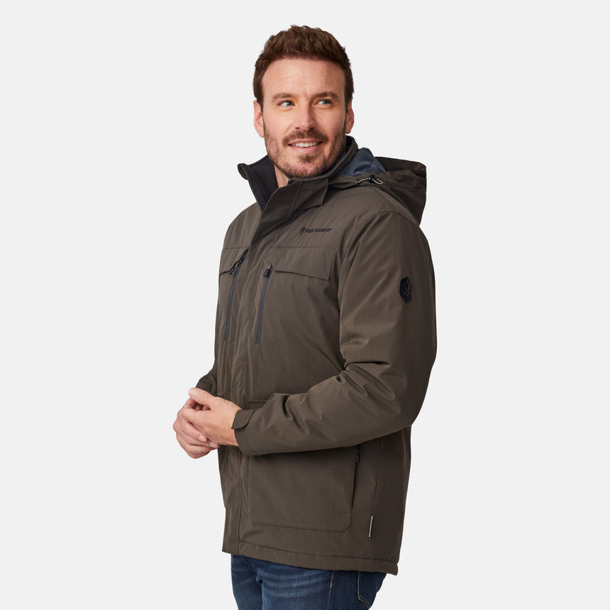 [Joe is 6'0" wearing size M.] Men’s Free Country brown hooded utility jacket featuring dual zippered chest pockets, flap waist pockets, and rugged outdoor styling—paired with blue jeans for a functional, adventure-ready look.