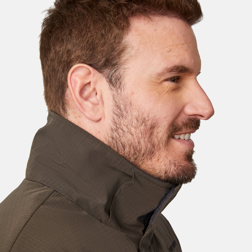 [Joe is 6'0" wearing size M.] Men’s Free Country brown hooded utility jacket featuring dual zippered chest pockets, flap waist pockets, and rugged outdoor styling—paired with blue jeans for a functional, adventure-ready look.