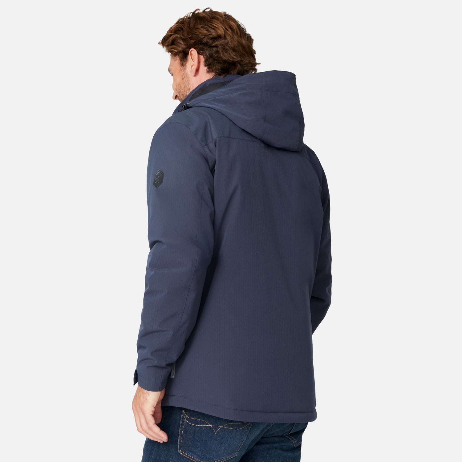 [Model is wearing size M.] A man wearing a navy blue hooded jacket, shown from a rear three-quarter angle against a light gray studio background.