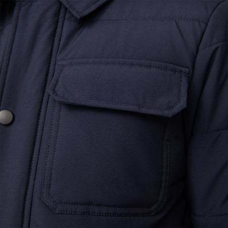 Close-up of the Free Country Boys' Trail Puffer Hoodie Shacket, a navy blue, water-resistant hoodie for kids, featuring a front pocket with flap and button, plus details of the collar and chest.