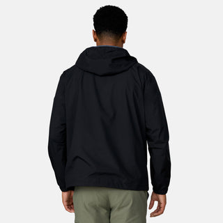 [Josiah is 6'3" wearing a size Medium.] Man wearing the Free Country Men's Agile II Windshear Jacket in Black, size M, made from lightweight wind and water resistant recycled polyester fabric and featuring an attached hood, inner phone pocket and elastic cuffs, styled with a black t shirt and black pants #color_ black
