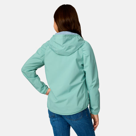A girl with long brown hair wears the Clearance Girls' High Stretch Windshear Jacket in light blue-green and blue jeans, standing with one hand on her hip and facing away from the camera against a plain background.