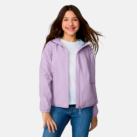 A young woman with long brown hair smiles while wearing the Clearance Girls' High Stretch Windshear Jacket in light purple over a white t-shirt and blue jeans, standing against a plain light background.