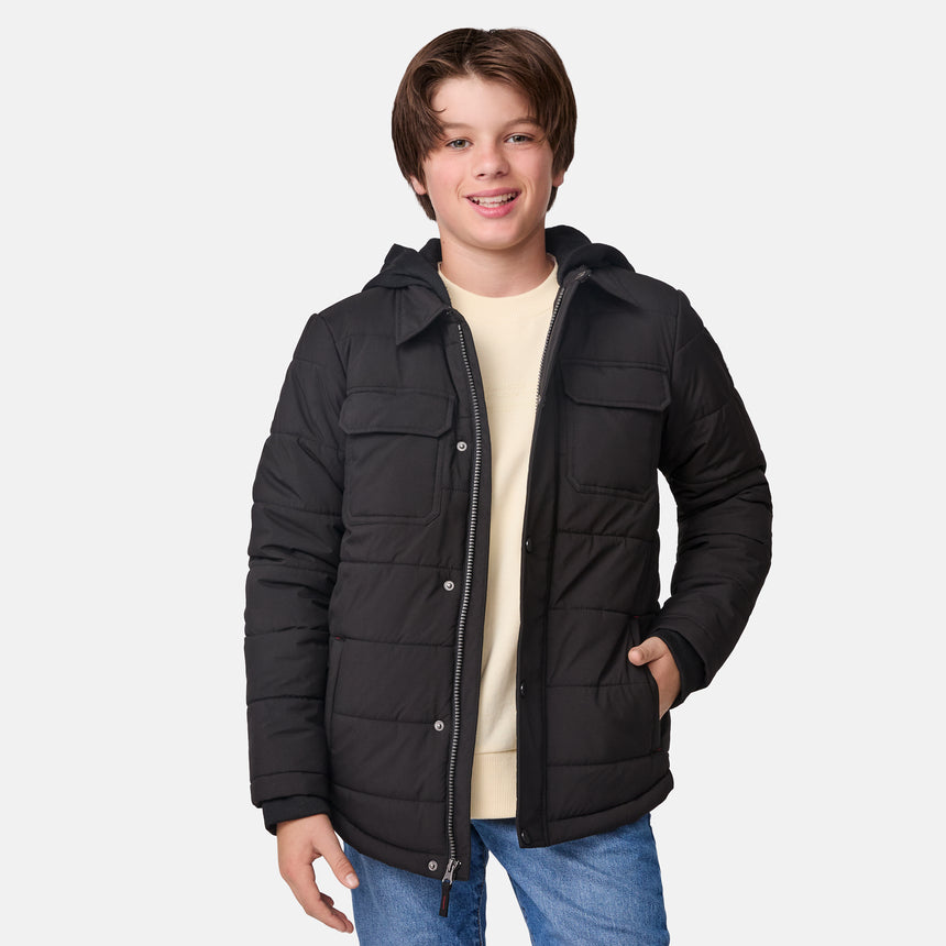 [River is wearing size M.] Model in a Free Country black quilted hooded jacket with button-up front, dual flap chest pockets, side hand pockets, and a branded emblem on the left sleeve—designed for modern outdoor wear, styled with blue jeans.