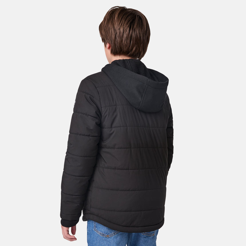 [River is wearing size M.] Model in a Free Country black quilted hooded jacket with button-up front, dual flap chest pockets, side hand pockets, and a branded emblem on the left sleeve—designed for modern outdoor wear, styled with blue jeans.