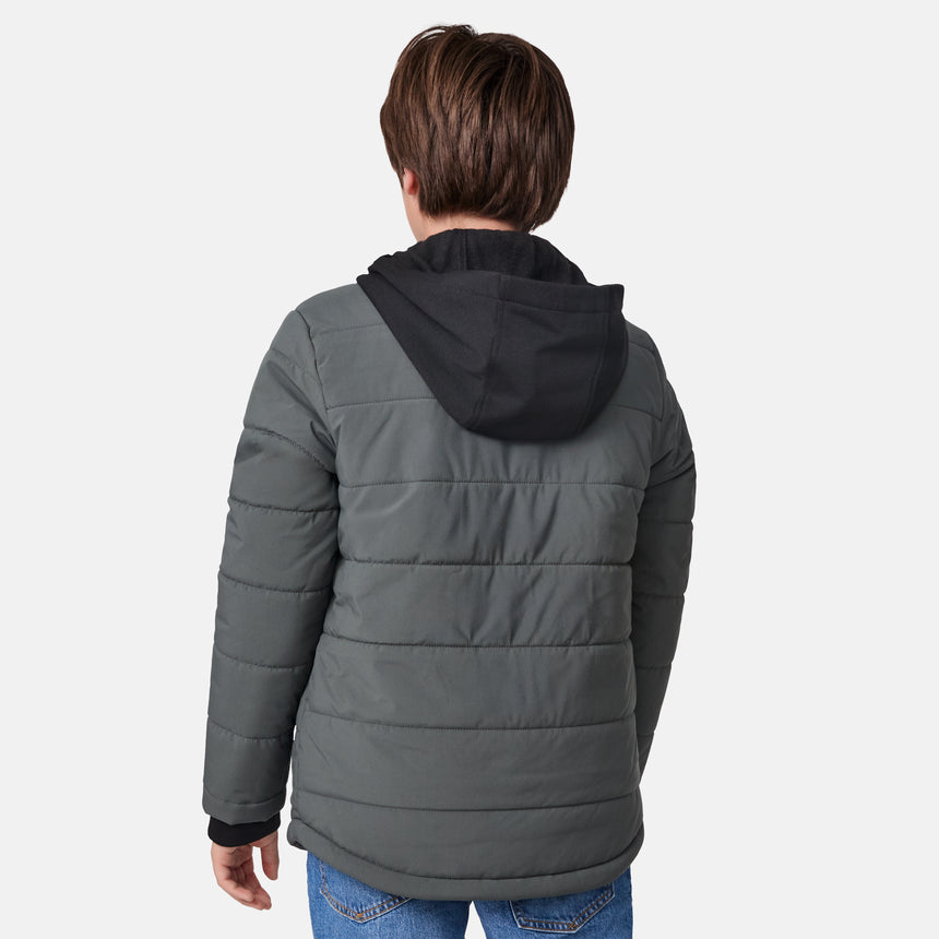 [River is wearing size M.] Model wearing a Free Country dark grey quilted hooded jacket featuring flap chest pockets, side hand pockets, and a partial front zip closure, paired with light innerwear and blue jeans—styled for casual outdoor comfort.