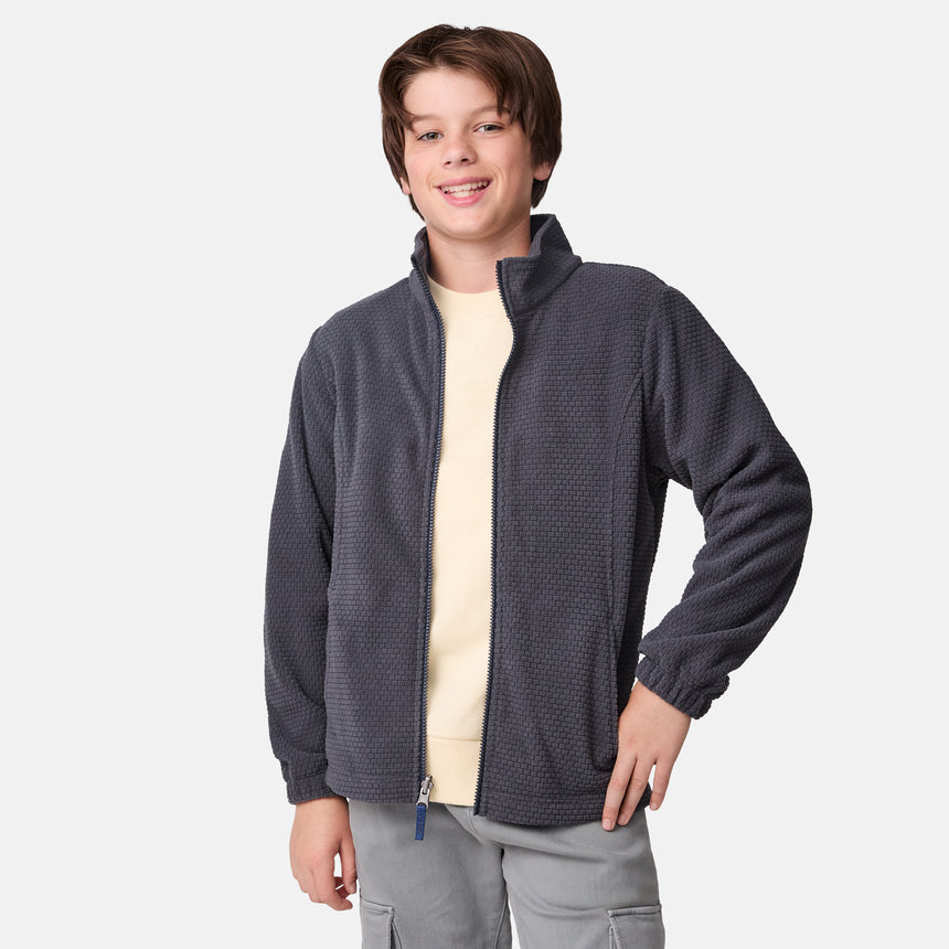 [River is wearing size M] Model in a two-tone Free Country system jacket featuring a dark gray upper shell and lighter gray lower body; complete with zip-out fleece liner, side-entry pockets, and an adjustable hood—styled with tonal gray pants for streamlined, cold-weather versatility.