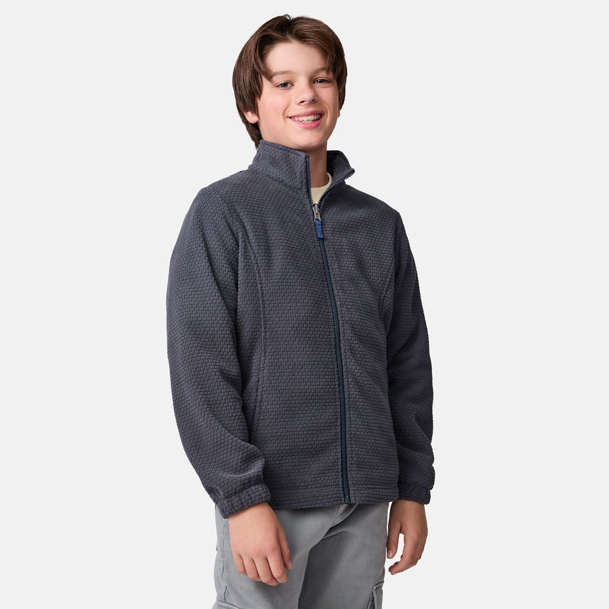 [River is wearing size M] Model in a two-tone Free Country system jacket featuring a dark gray upper shell and lighter gray lower body; complete with zip-out fleece liner, side-entry pockets, and an adjustable hood—styled with tonal gray pants for streamlined, cold-weather versatility.