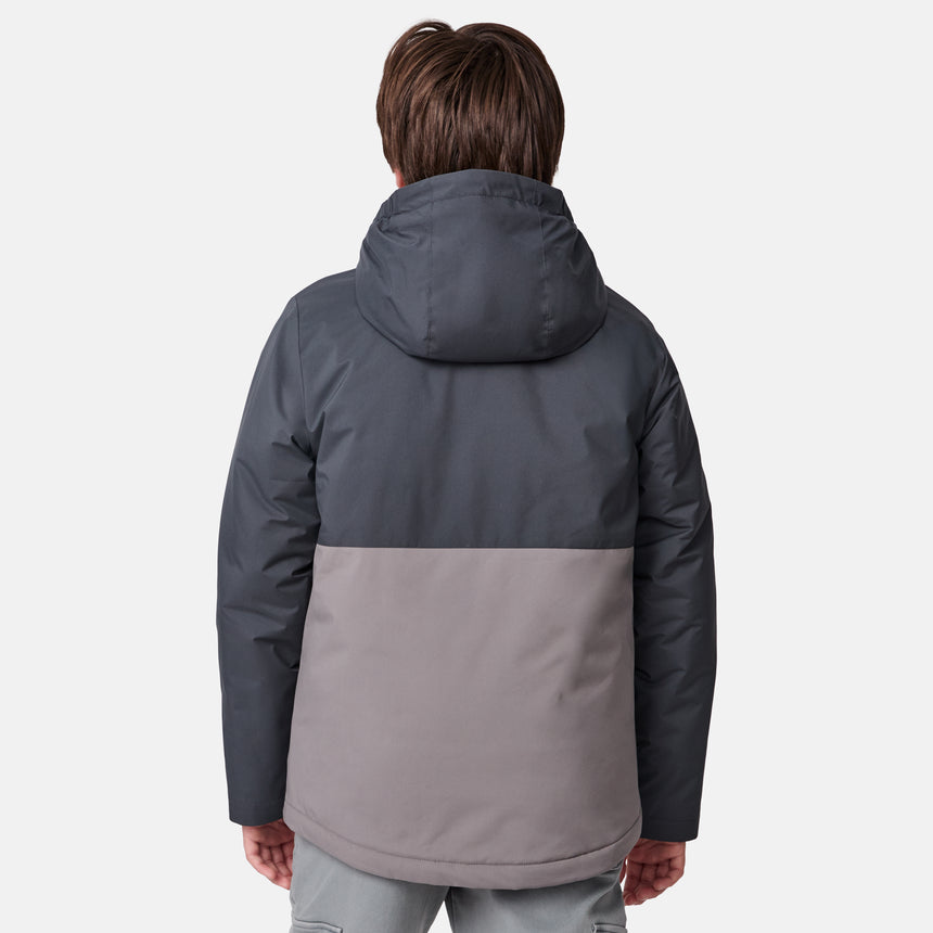[River is wearing size M] Model in a two-tone Free Country system jacket featuring a dark gray upper shell and lighter gray lower body; complete with zip-out fleece liner, side-entry pockets, and an adjustable hood—styled with tonal gray pants for streamlined, cold-weather versatility.