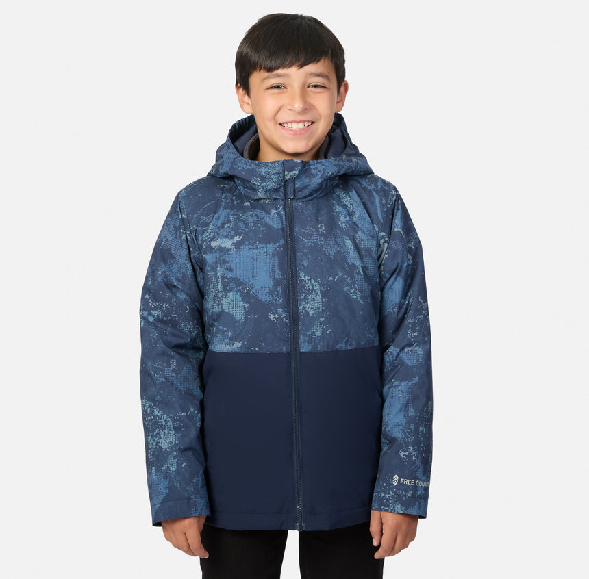 A boy wearing a navy blue Free Country Boys’ High Stretch 3-in-1 Systems Jacket featuring a patterned upper section.