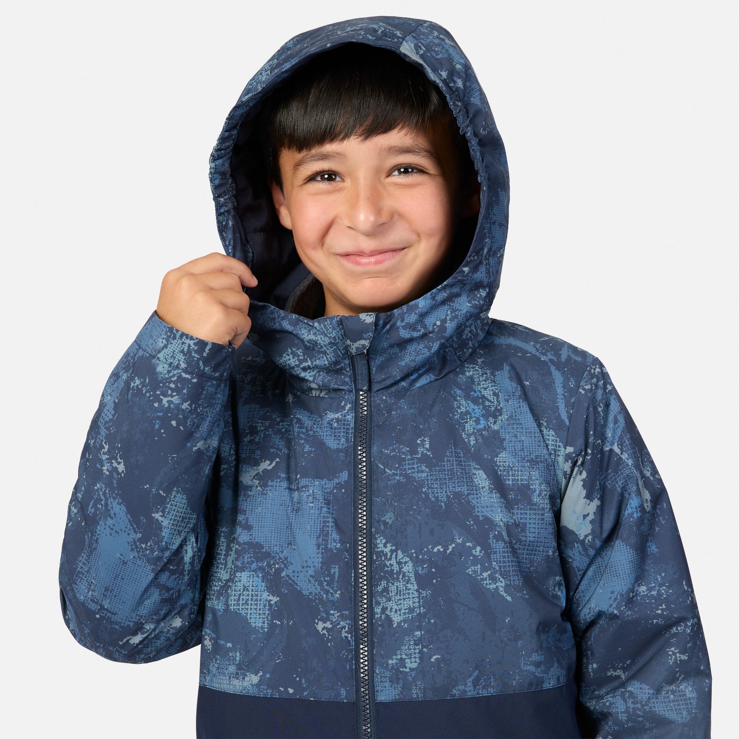 A boy wearing a blue Boys’ High Stretch 3-in-1 Systems Jacket with a hood and a subtle geometric pattern.