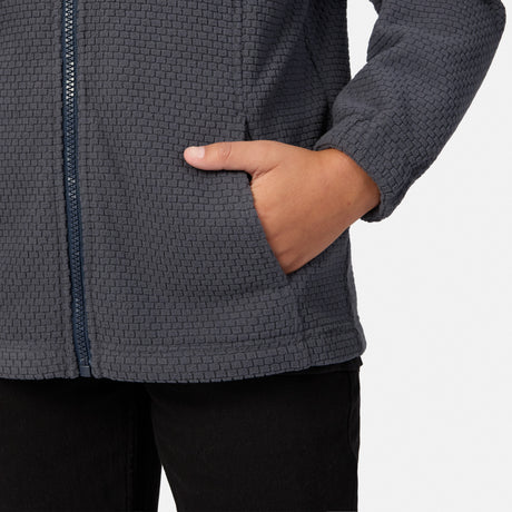Close-up of a person wearing a charcoal gray, high-stretch textured Free Country Boys’ High Stretch 3-in-1 Systems Jacket with a zippered pocket and their hand inside.