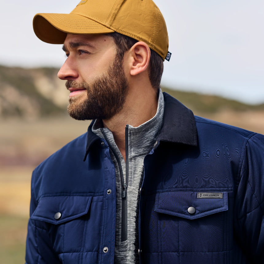 Man wearing a blue jacket and yellow cap outdoors
