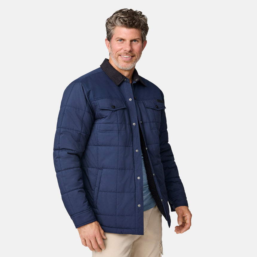 [Kolby is 6'2" wearing size M.] Men’s Free Country dark blue quilted jacket with button-up front, flap chest pockets, and contrasting corduroy-style collar—styled with light-colored pants for a rugged, heritage-inspired outdoor look.