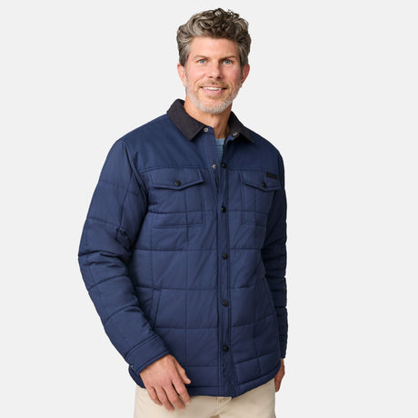 [Kolby is 6'2" wearing size M.] Men’s Free Country dark blue quilted jacket with button-up front, flap chest pockets, and contrasting corduroy-style collar—styled with light-colored pants for a rugged, heritage-inspired outdoor look.