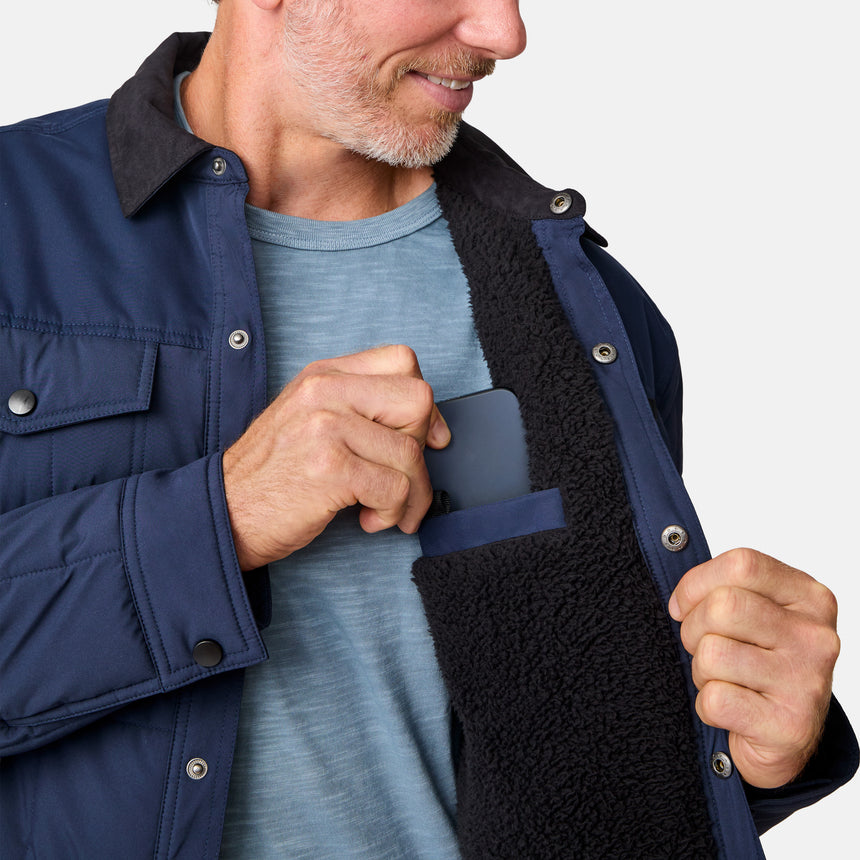 [Kolby is 6'2" wearing size M.] Men’s Free Country dark blue quilted jacket with button-up front, flap chest pockets, and contrasting corduroy-style collar—styled with light-colored pants for a rugged, heritage-inspired outdoor look.
